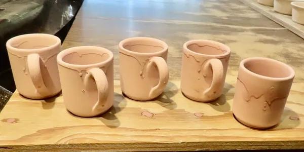Unfired ceramic mugs ready for glazing