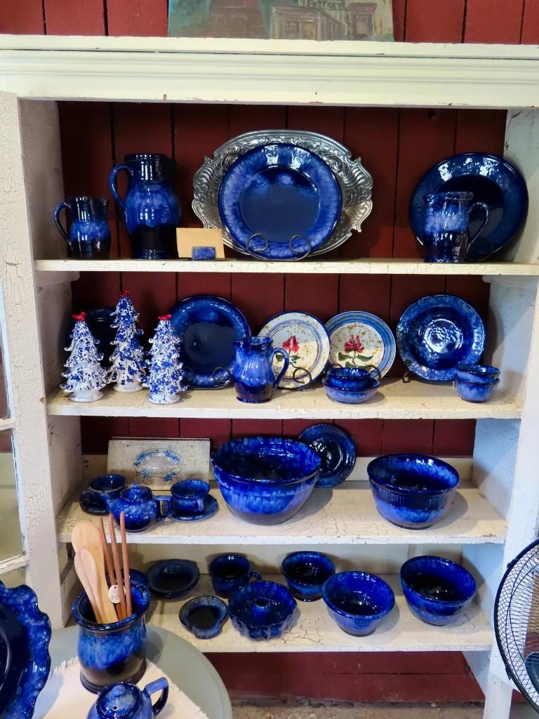 Deep blue ceramic dishware and bowls displayed on painted shelves