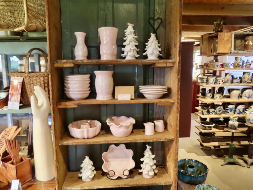 Pink glazed vases, bowls, and ceramic trees on a rustic wooden shelf